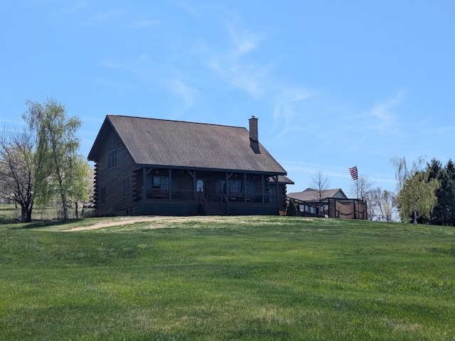 back of property featuring log siding, a chimney, and a yard