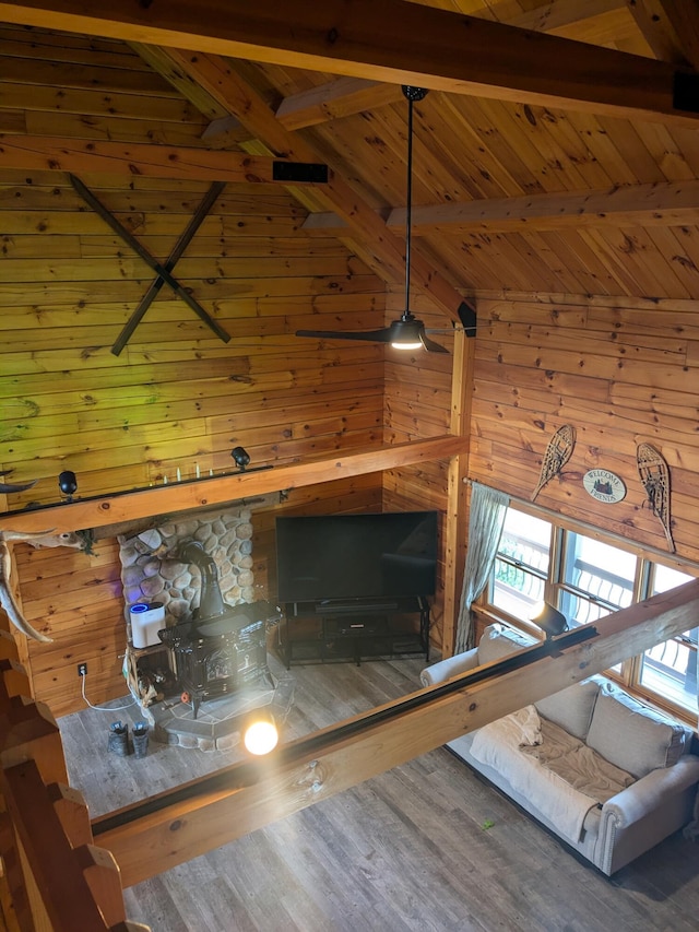 unfurnished living room featuring beamed ceiling, wood walls, wood finished floors, and wood ceiling