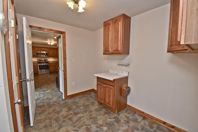 2115 Upper Smith Gap Rd, Saylorsburg, PA 18353 - kitchen with stainless steel appliances, dark stone finish flooring, brown cabinetry, light countertops, and a chandelier