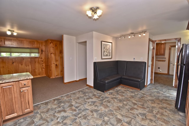 2115 Upper Smith Gap Rd, Saylorsburg, PA 18353 - kitchen with dark stone finish flooring, freestanding refrigerator, rail lighting, wooden walls, and brown cabinets