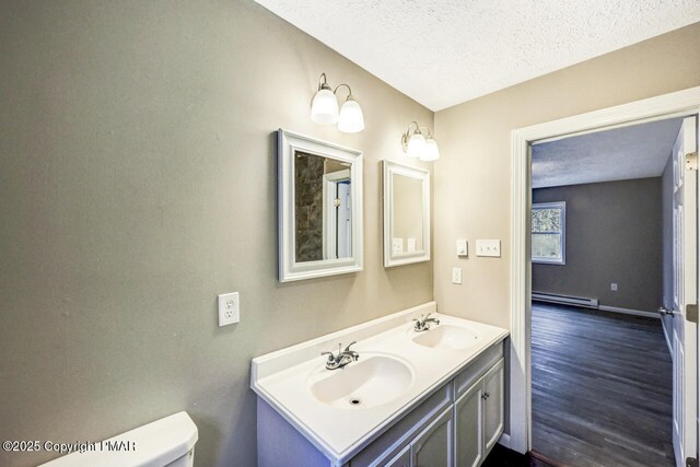 bathroom with baseboard heating, hardwood / wood-style floors, vanity, a textured ceiling, and toilet