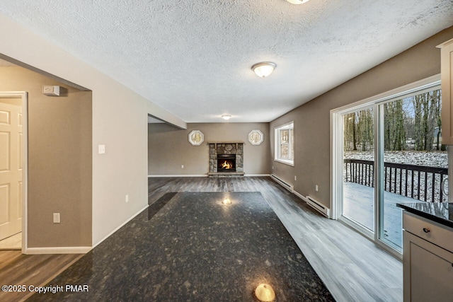 unfurnished living room featuring a baseboard radiator, a fireplace, and wood finished floors