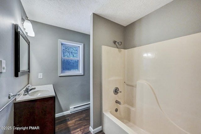 bathroom featuring  shower combination, baseboard heating, vanity, wood-type flooring, and a textured ceiling