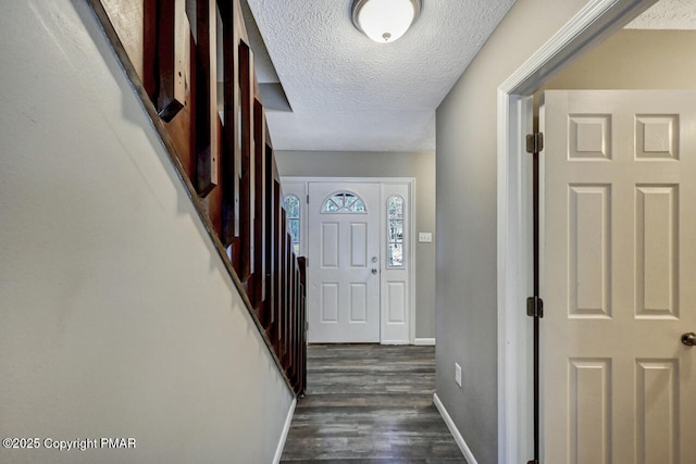 entrance foyer featuring a textured ceiling, dark wood-style flooring, and baseboards