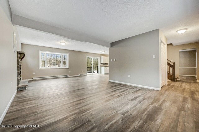 unfurnished living room with a textured ceiling, a baseboard radiator, and wood-type flooring