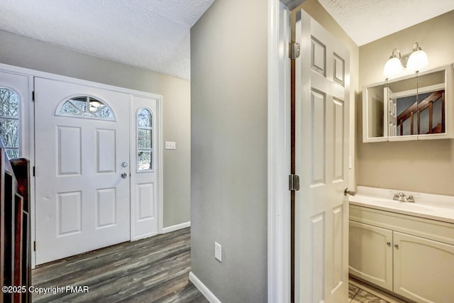 entryway with dark wood-style flooring, a textured ceiling, and baseboards