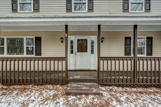 snow covered property entrance featuring a porch