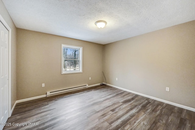 spare room featuring a baseboard radiator, wood-type flooring, and a textured ceiling