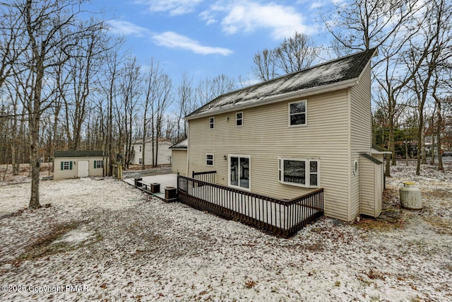 snow covered house with a wooden deck and an outdoor structure