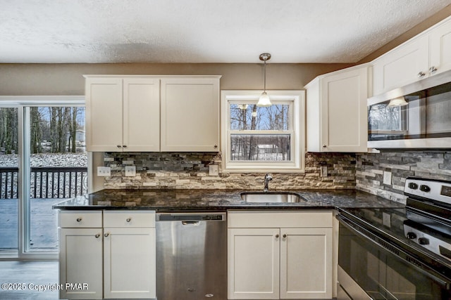 kitchen featuring pendant lighting, sink, stainless steel appliances, and dark stone countertops