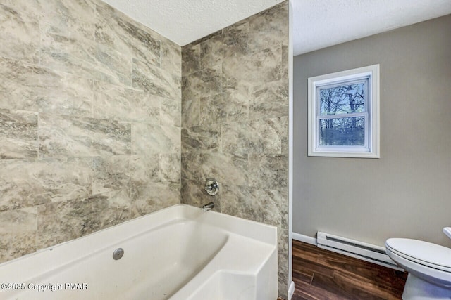 bathroom featuring a tub to relax in, a baseboard radiator, toilet, a textured ceiling, and wood finished floors