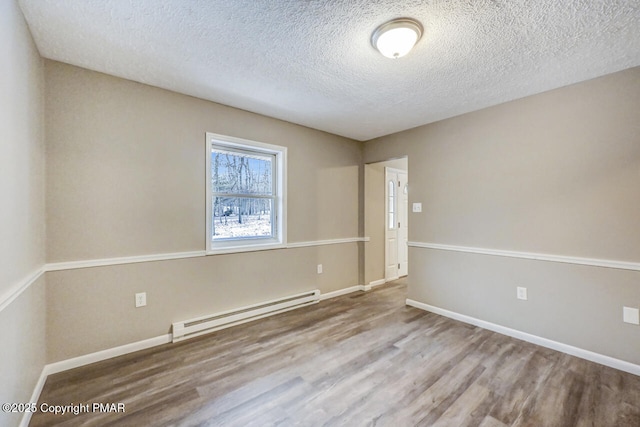 spare room featuring wood-type flooring, a textured ceiling, and baseboard heating