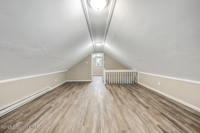 additional living space featuring hardwood / wood-style flooring, a baseboard radiator, and vaulted ceiling