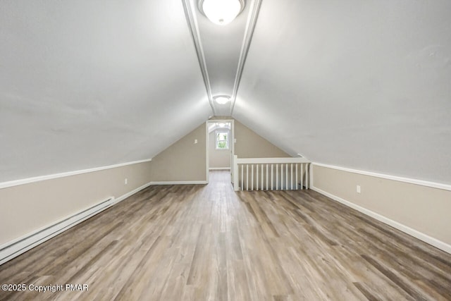 additional living space featuring baseboards, vaulted ceiling, baseboard heating, and wood finished floors