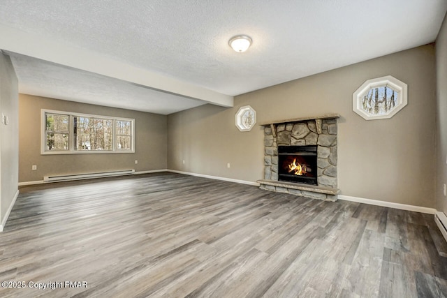 unfurnished living room featuring a baseboard heating unit, a stone fireplace, a textured ceiling, wood finished floors, and baseboards