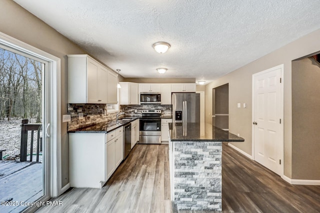 kitchen featuring sink, hardwood / wood-style flooring, appliances with stainless steel finishes, backsplash, and white cabinets