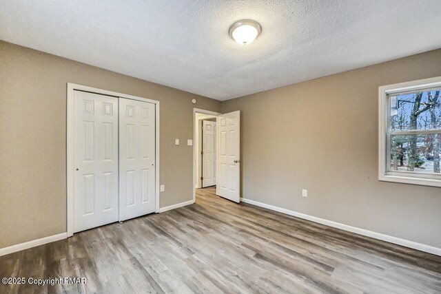 unfurnished bedroom with light hardwood / wood-style flooring, a closet, and a textured ceiling