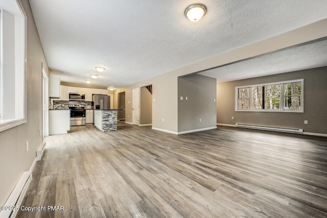 unfurnished living room with light wood finished floors, baseboards, a baseboard radiator, baseboard heating, and a textured ceiling