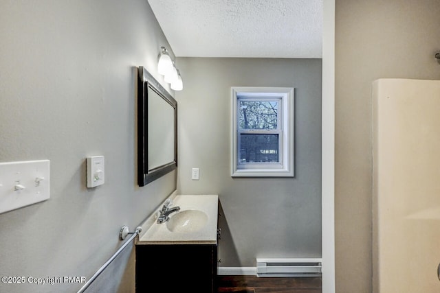 bathroom with vanity, wood-type flooring, a baseboard heating unit, and a textured ceiling