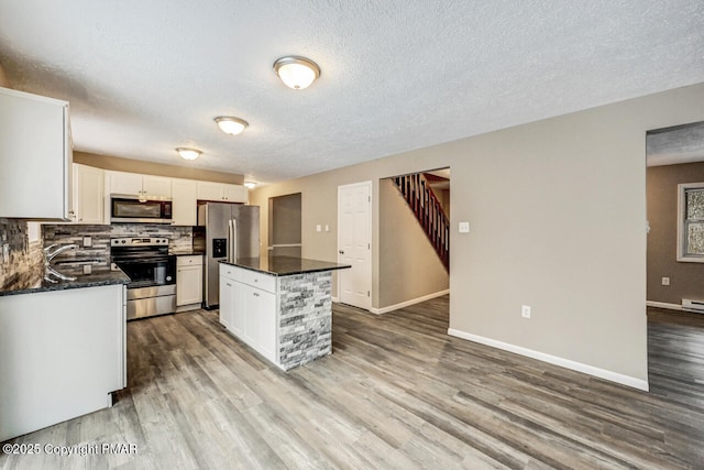 kitchen with sink, stainless steel appliances, tasteful backsplash, white cabinets, and a kitchen island