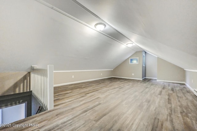 additional living space featuring baseboards, vaulted ceiling, and wood finished floors