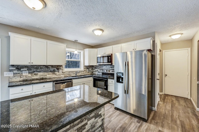 kitchen featuring white cabinets, light wood finished floors, tasteful backsplash, and stainless steel appliances