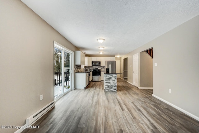 kitchen featuring hardwood / wood-style floors, white cabinetry, decorative backsplash, a baseboard heating unit, and stainless steel appliances