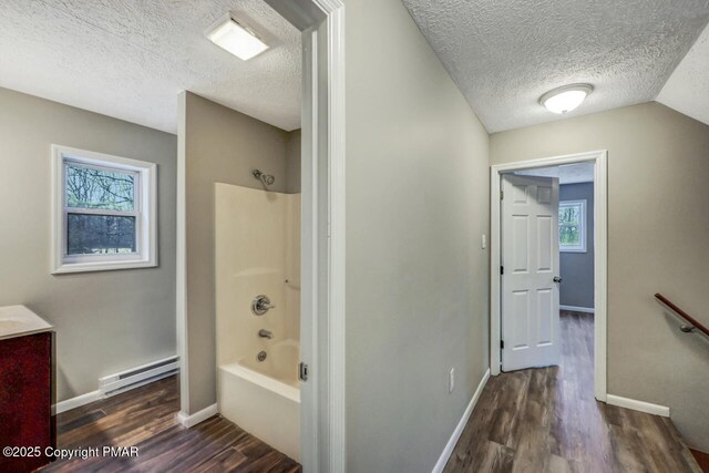 bathroom with hardwood / wood-style flooring, a baseboard heating unit, a wealth of natural light, and bathtub / shower combination