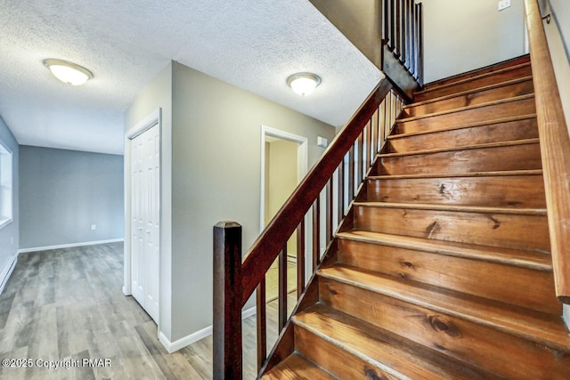 staircase featuring hardwood / wood-style flooring and a textured ceiling