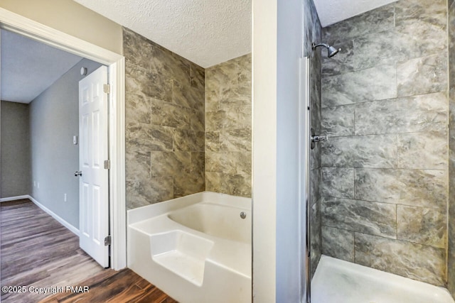 bathroom with wood-type flooring, a textured ceiling, and separate shower and tub