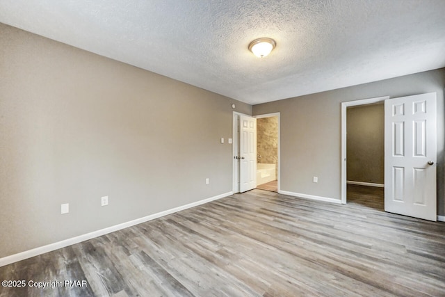 interior space featuring a textured ceiling, baseboards, and wood finished floors