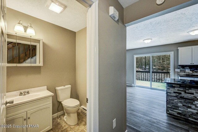 bathroom with vanity, a textured ceiling, a baseboard radiator, and toilet