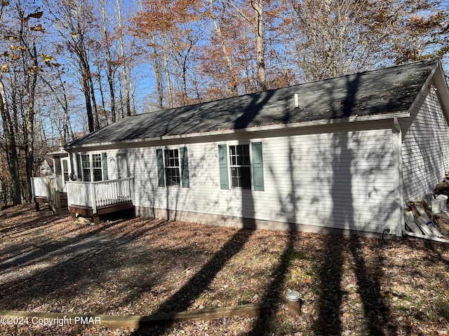 view of side of home with a shingled roof and a wooden deck