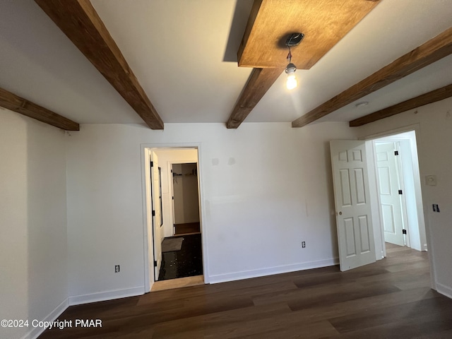 interior space with baseboards, wood finished floors, and beamed ceiling