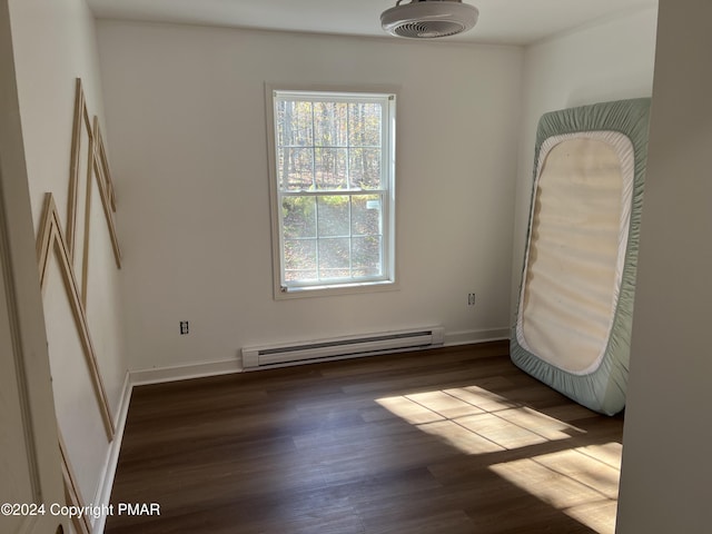 spare room featuring baseboard heating, wood finished floors, and baseboards