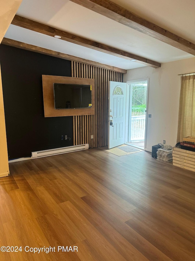 unfurnished living room with beam ceiling, a baseboard heating unit, and wood finished floors