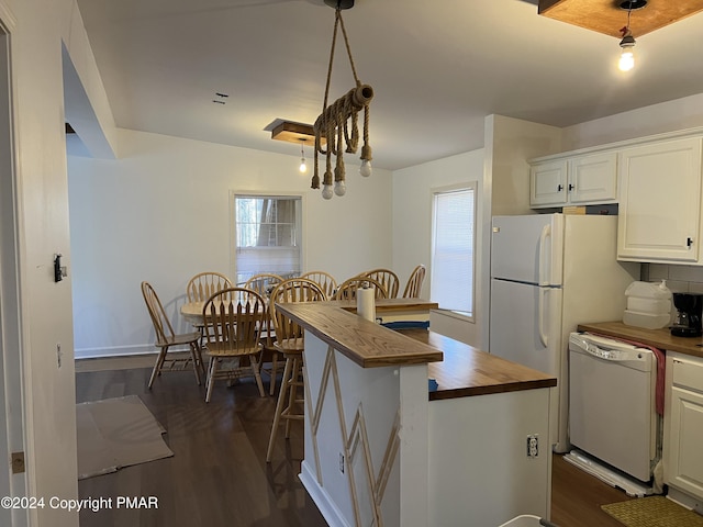 kitchen featuring a breakfast bar, butcher block countertops, dark wood-type flooring, and dishwasher