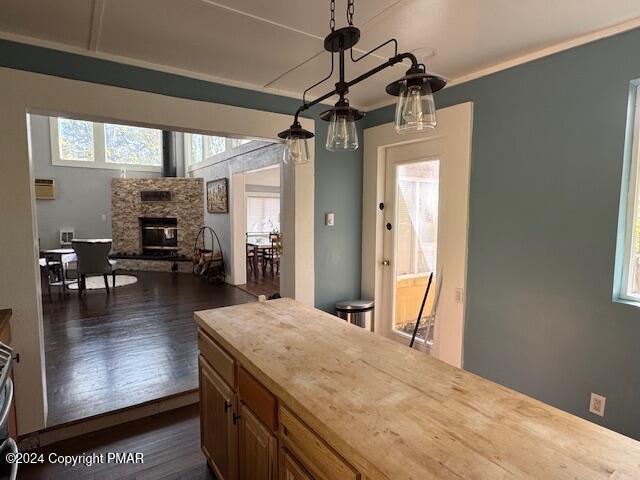 kitchen featuring open floor plan, light countertops, a stone fireplace, and dark wood-style flooring