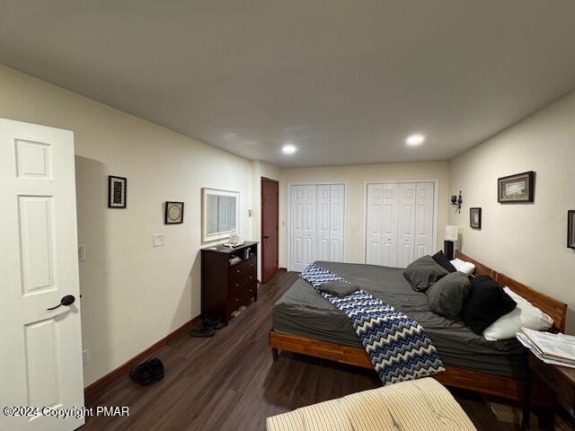 bedroom with dark wood-style floors, recessed lighting, baseboards, and two closets