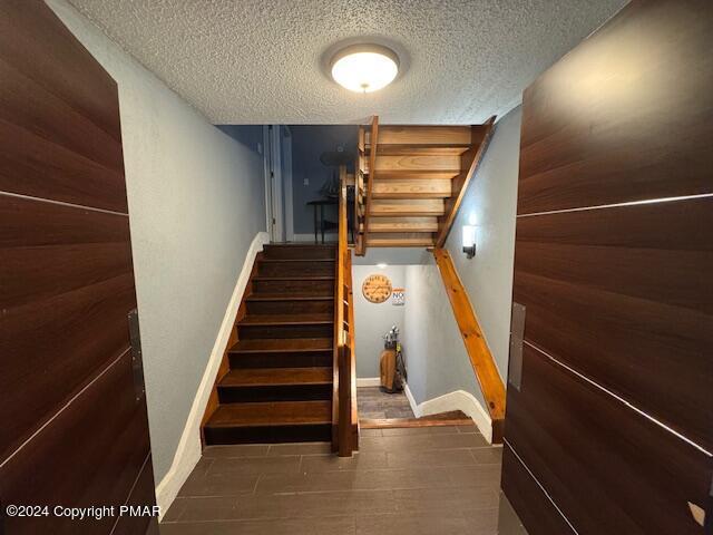 stairs featuring a textured ceiling and baseboards