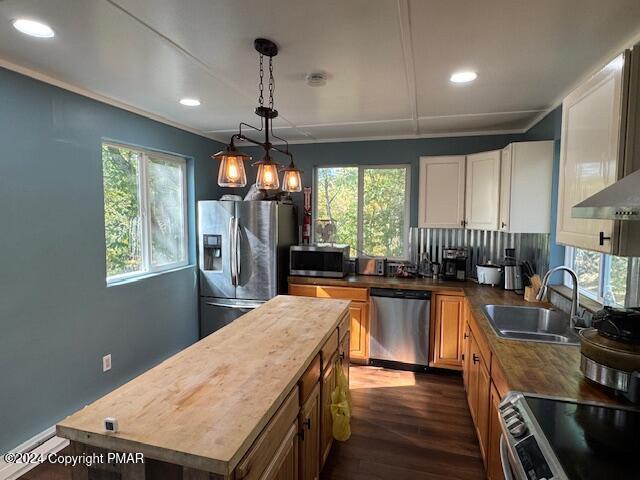 kitchen with stainless steel appliances, dark wood-style flooring, a sink, white cabinetry, and a center island