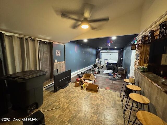 interior space featuring lofted ceiling, ceiling fan, a bar, and a baseboard radiator