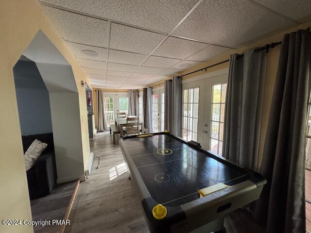 game room featuring wood finished floors, a drop ceiling, and french doors