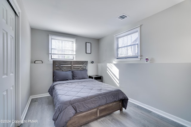 bedroom with baseboards, a closet, visible vents, and wood finished floors