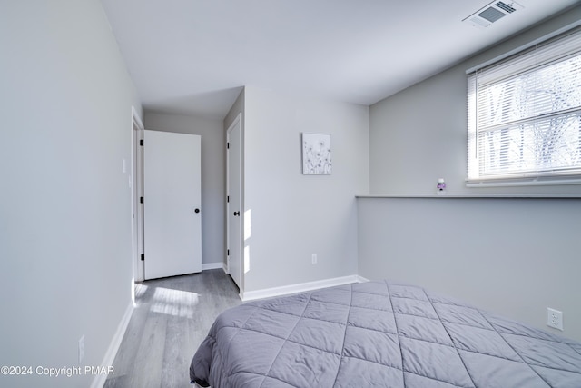 bedroom featuring baseboards, visible vents, and wood finished floors