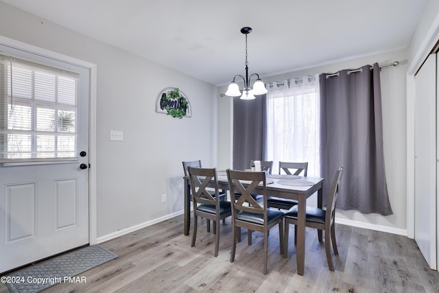 dining area featuring baseboards, light wood finished floors, and an inviting chandelier