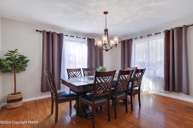 dining area with a notable chandelier, hardwood / wood-style flooring, and baseboards