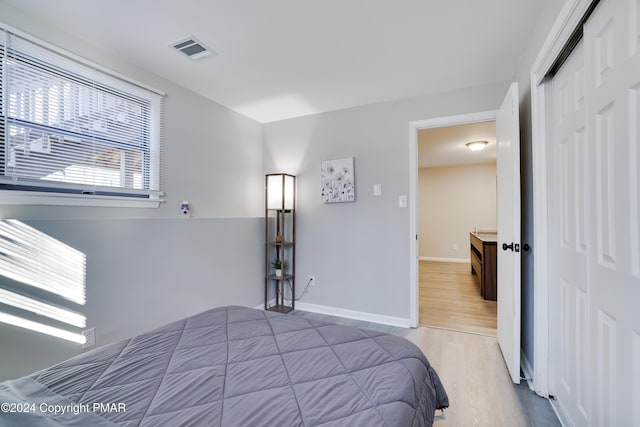 bedroom featuring a closet, wood finished floors, visible vents, and baseboards