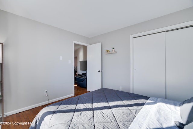 bedroom with a closet, wood finished floors, and baseboards