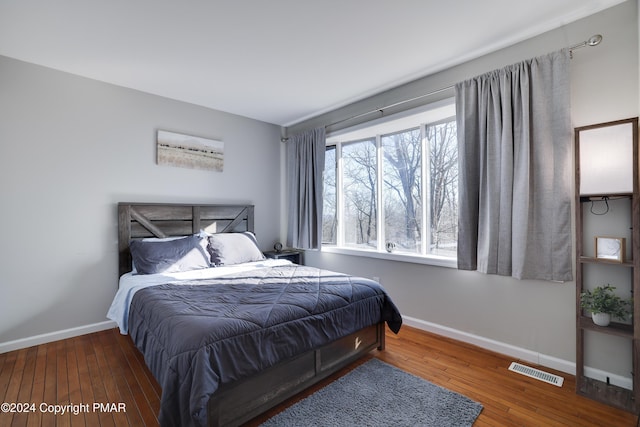 bedroom with baseboards, visible vents, and hardwood / wood-style floors